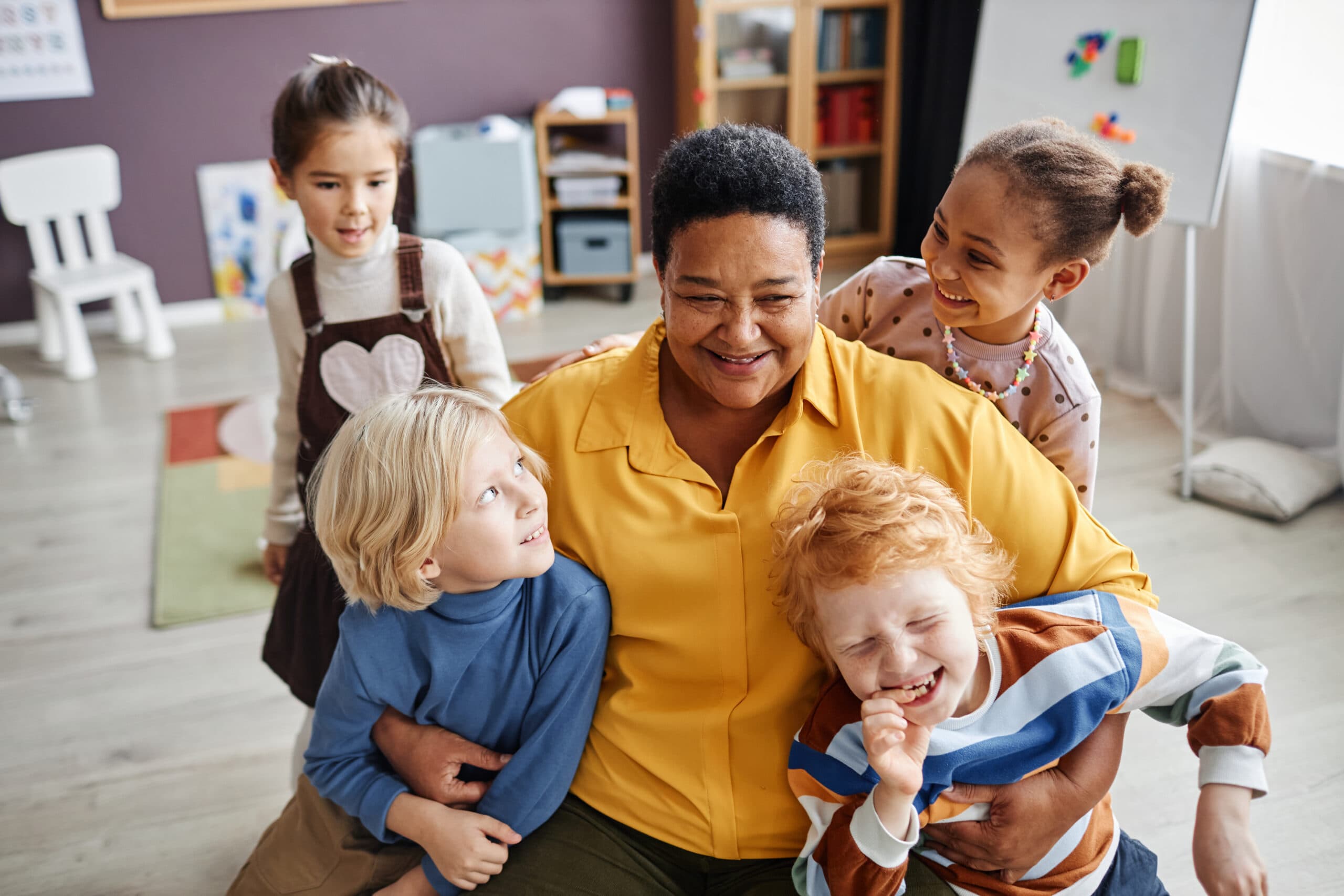 Happy mature teacher embracing two adorable boys while having fun